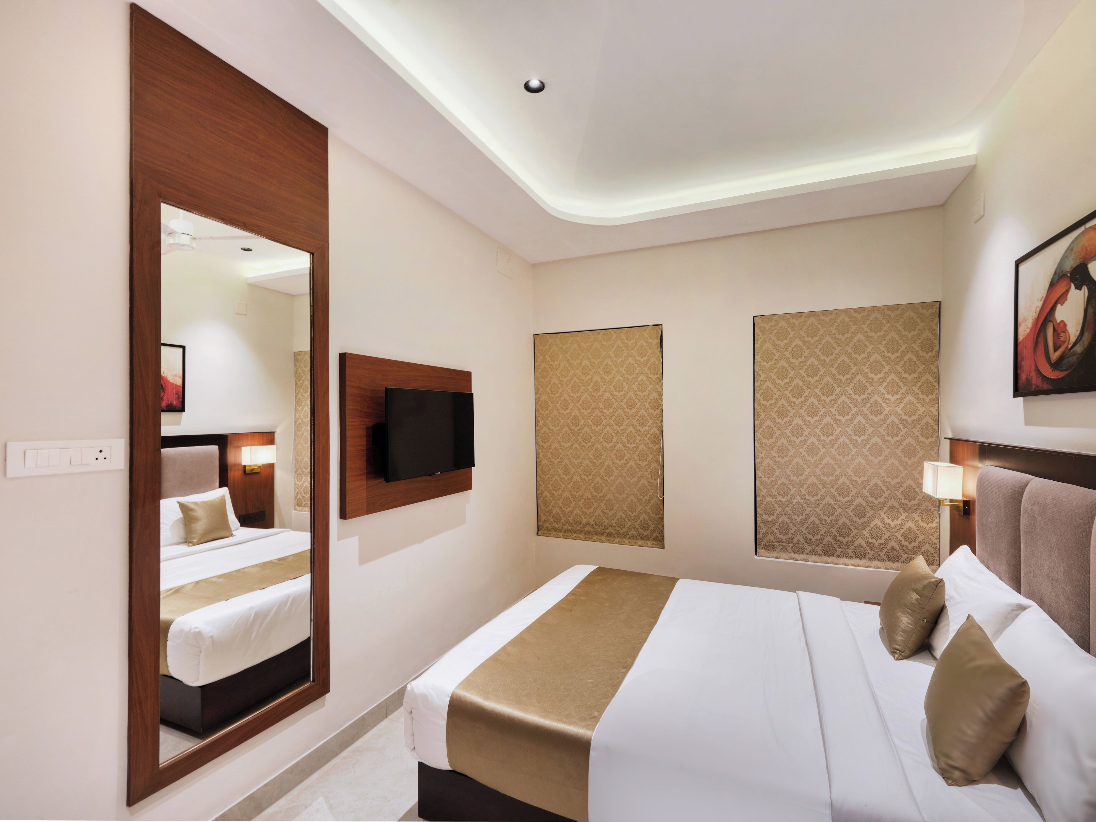Een hotelkamer met een groot bed, een flatscreen televisie aan de muur en een spiegel.