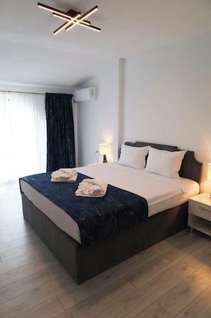 A modern hotel room with a large bed, bedside lamps, and a ceiling light fixture.