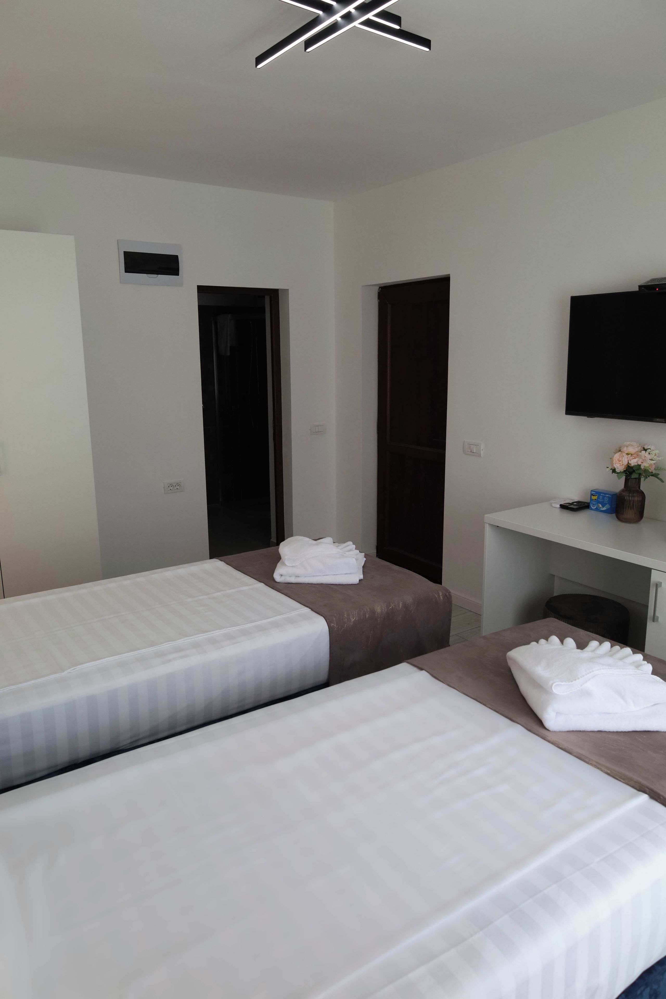 A hotel room with two beds, a desk, a television, and a door.
