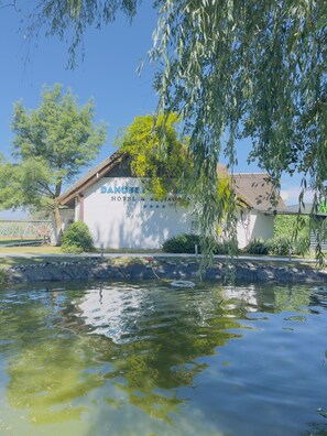A hotel with a sign reading 'Danube Hotel & Restaurant' surrounded by greenery and a body of water.