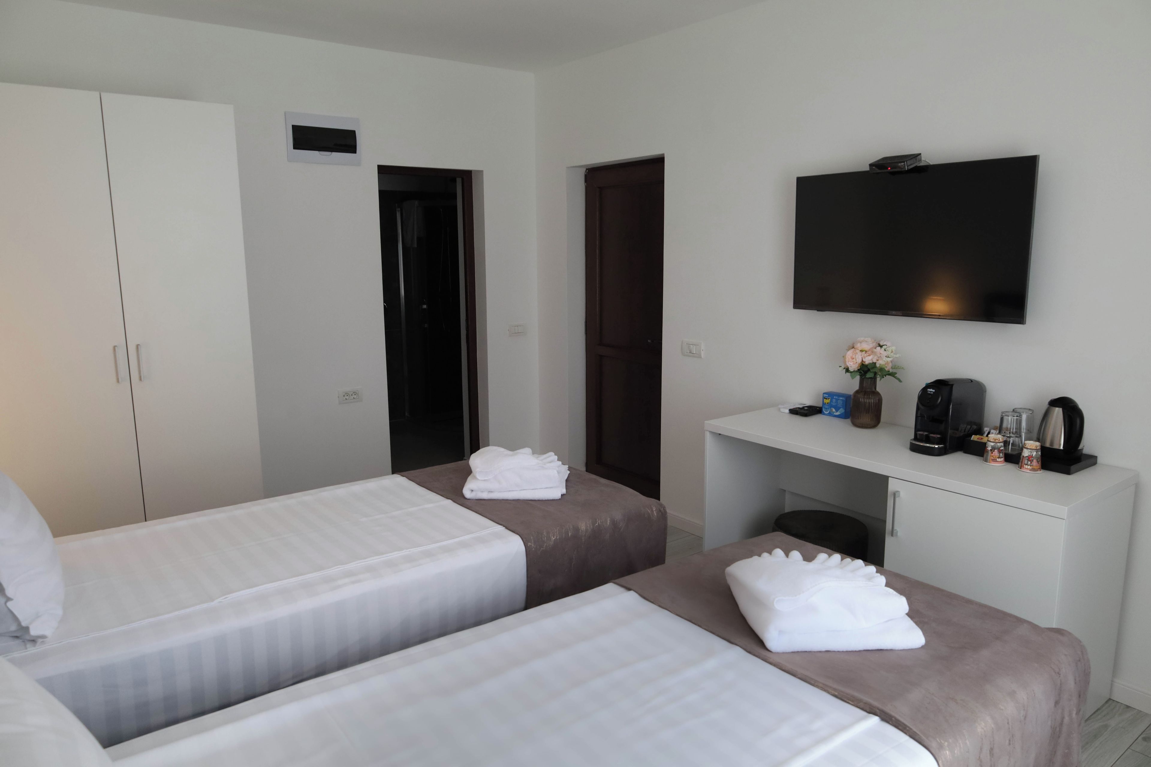 A hotel room with two beds, a desk with a television, and a coffee maker.