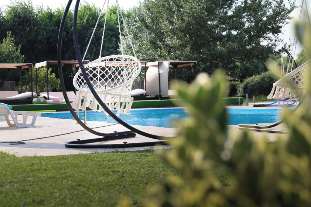 Zona de piscina con sillas de descanso y una hamaca.