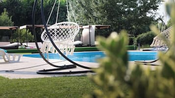 Zona de piscina con sillas de descanso y una hamaca.