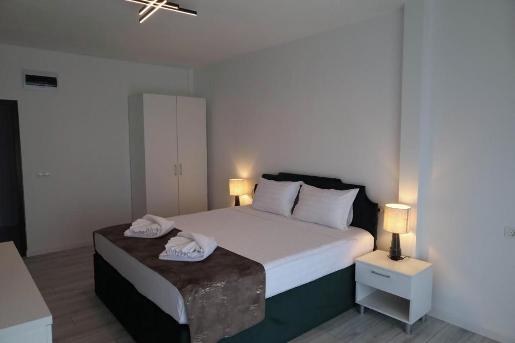 A hotel room with a bed, bedside lamps, a wardrobe, and a small bedside table.