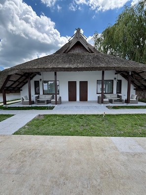A traditional thatched-roof building with a symmetrical facade, large windows, and a central door.
