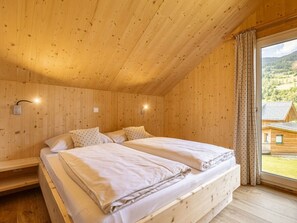 A wooden cabin room with a bed, two bedside tables, and a window with curtains. - Cabin With 1 Bedroom (Sankt Georgen am Kreischberg)