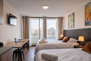 A hotel room with a desk, two beds, a TV, and a city view. - Edificio Agustinas by Domus Travels (Santiago)