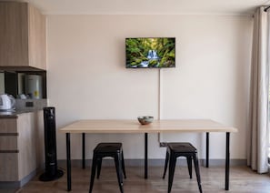 A minimalist kitchen with a wooden table and two black stools, a kettle, and a water heater. - Edificio Agustinas by Domus Travels (Santiago)