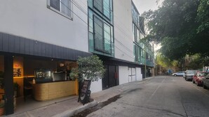 Une vue de rue avec un restaurant sur la gauche, un trottoir et des voitures garées sur la droite.