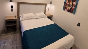 Une chambre à coucher comprenant un lit, deux tables de chevet, un ventilateur de plafond et une œuvre d’art accrochée au mur.