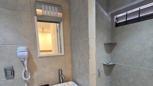 Une salle de bain équipée d’une douche, d’un lavabo, d’un sèche-cheveux et d’un miroir.