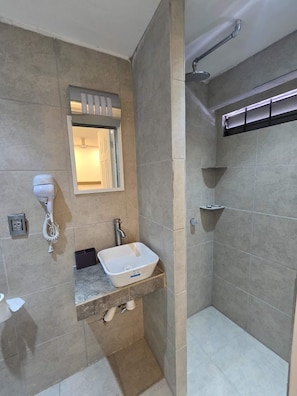 Casa de banho com chuveiro, lavatório, secador de cabelo e espelho.