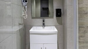 Une salle de bain moderne avec un meuble-lavabo blanc, un miroir, un sèche-cheveux et un distributeur de savon.