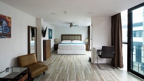 Une chambre d’hôtel avec un lit, un bureau et une chaise, une télévision et une grande fenêtre.