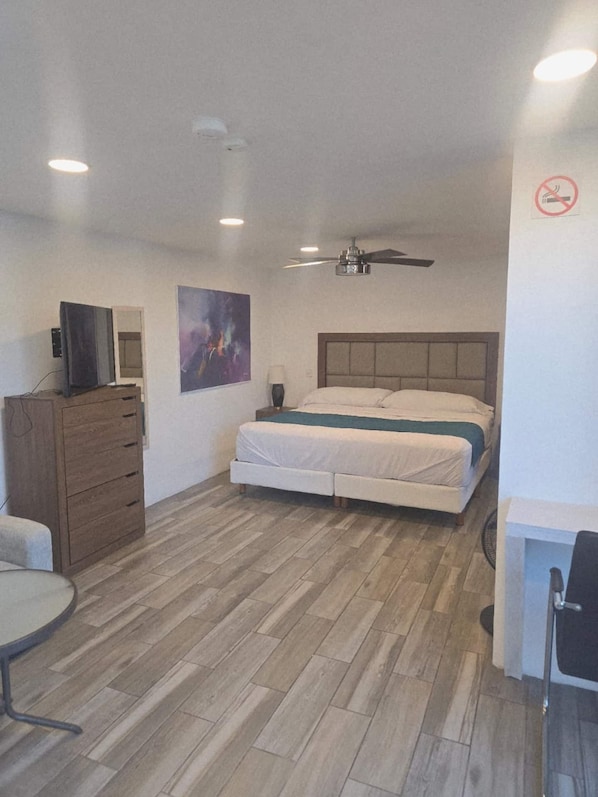 Quarto com cama, penteadeira, televisão e ventoinha no teto.