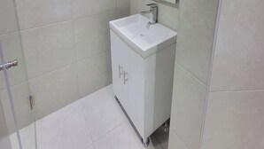 Une salle de bain avec un lavabo blanc, un miroir et un espace douche.