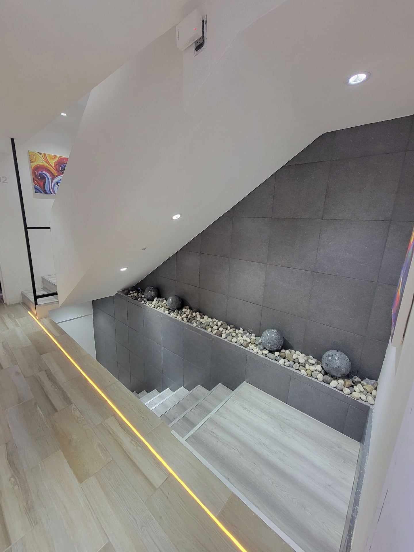 A modern staircase with a concrete wall and a decorative rock ledge.