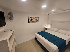 Ein Schlafzimmer mit Bett, Nachttischen, einem an der Wand befestigten Fernseher, einem Deckenventilator und einem Gemälde.
