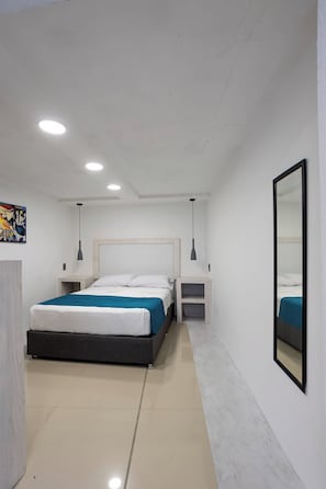 Quarto moderno com cama, mesas de cabeceira, um espelho e um quadro na parede.