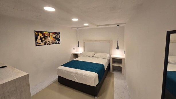 Une chambre à coucher moderne avec un lit, des tables de chevet, un tableau et un miroir.