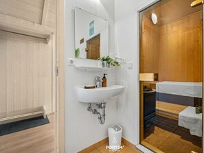 A modern bathroom with a white sink, mirror, and wooden paneling. - Holiday Home With 1 Bedroom (Braunlage)