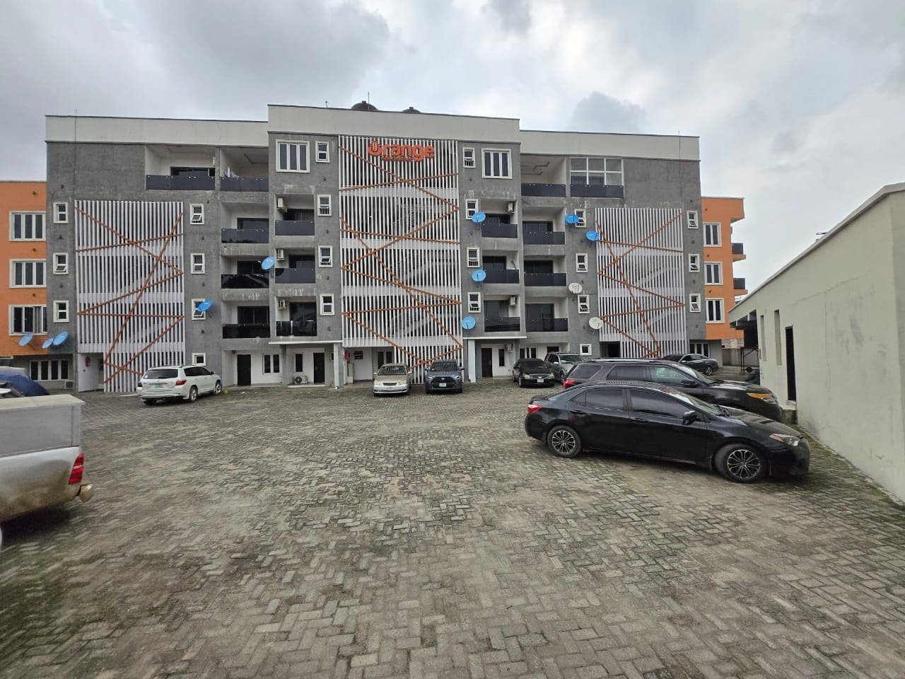 A multi-story building with a parking area in front.