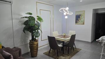 Una zona de menjador amb taula, cadires, una planta i un llum modern.