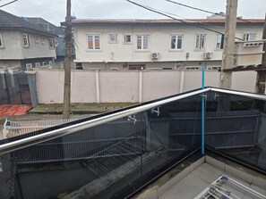 Un edificio residencial con varias ventanas, un acceso con portón y una unidad de aire acondicionado visible.