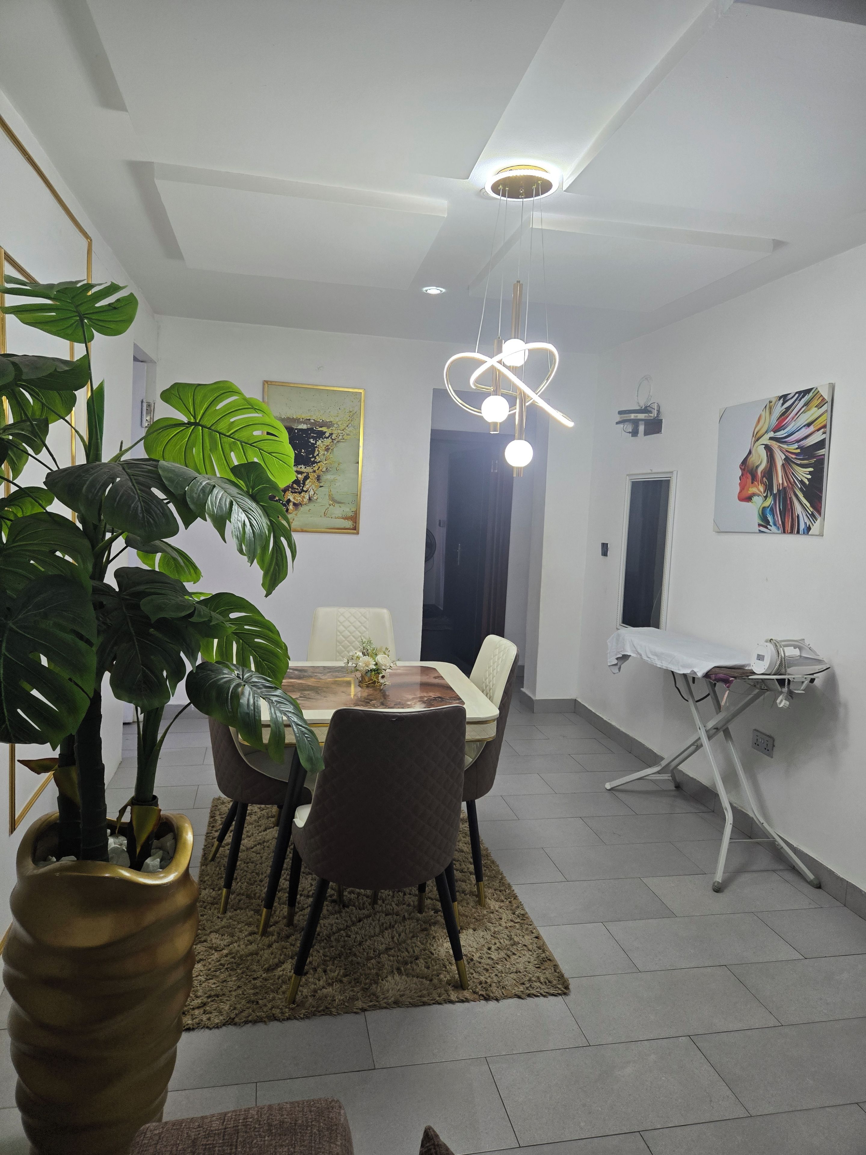 Et moderne spiseområde med et rundt bord, stole, en potteplante og en lampe i loftet.