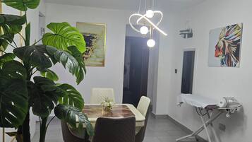Et moderne spiseområde med et rundt bord, stole, en potteplante og en lampe i loftet.