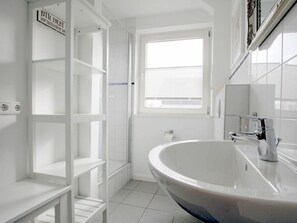 A bathroom with a large white sink, a window, and a white shelving unit. - E2 "nordmeer" at Feldstr. 18 (Wyk auf Foehr)