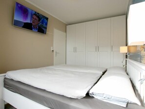 A bedroom with a bed, a television mounted on the wall, and a wardrobe. - E2 "nordmeer" at Feldstr. 18 (Wyk auf Foehr)