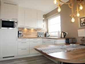 A modern kitchen with white cabinets, a built-in microwave, a coffee maker, and a toaster. - E2 "nordmeer" at Feldstr. 18 (Wyk auf Foehr)