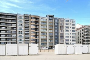 A multi-story residential building with balconies, a parking area, and a clear sky. - Renovated Apartment in Knokke-heist With Views (Knokke-Heist)