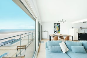 A modern living room with a view of the beach, a dining area, and a kitchen. - Renovated Apartment in Knokke-heist With Views (Knokke-Heist)