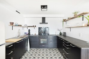 A modern kitchen with a central island, black cabinetry, and a patterned floor. - Renovated Apartment in Knokke-heist With Views (Knokke-Heist)