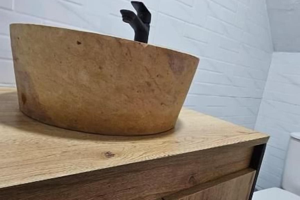 Un meuble-lavabo en bois avec un lavabo en cuvette et des toilettes dans un coin.