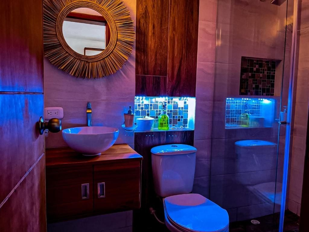 Un baño moderno con un espejo grande, un tocador de madera, un lavabo e inodoro.