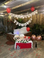 Un espacio interior decorado con un banderín, globos y una mesa con mantel rojo.