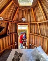 Un interior de madera con una cama, un tragaluz y vistas al exterior.