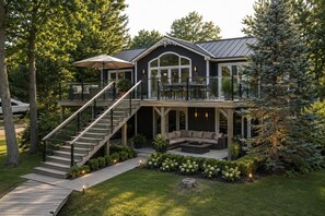 A two-story house with a covered patio, outdoor seating, and a staircase leading to the upper level.
