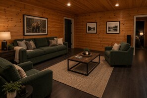 A cozy living room with a green sofa, a coffee table, and framed pictures on the walls.