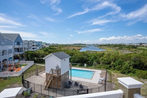 A residential area with a swimming pool, a small wooden structure, and a view of a lake. - Water views with pool and hot tub (North Topsail Beach)