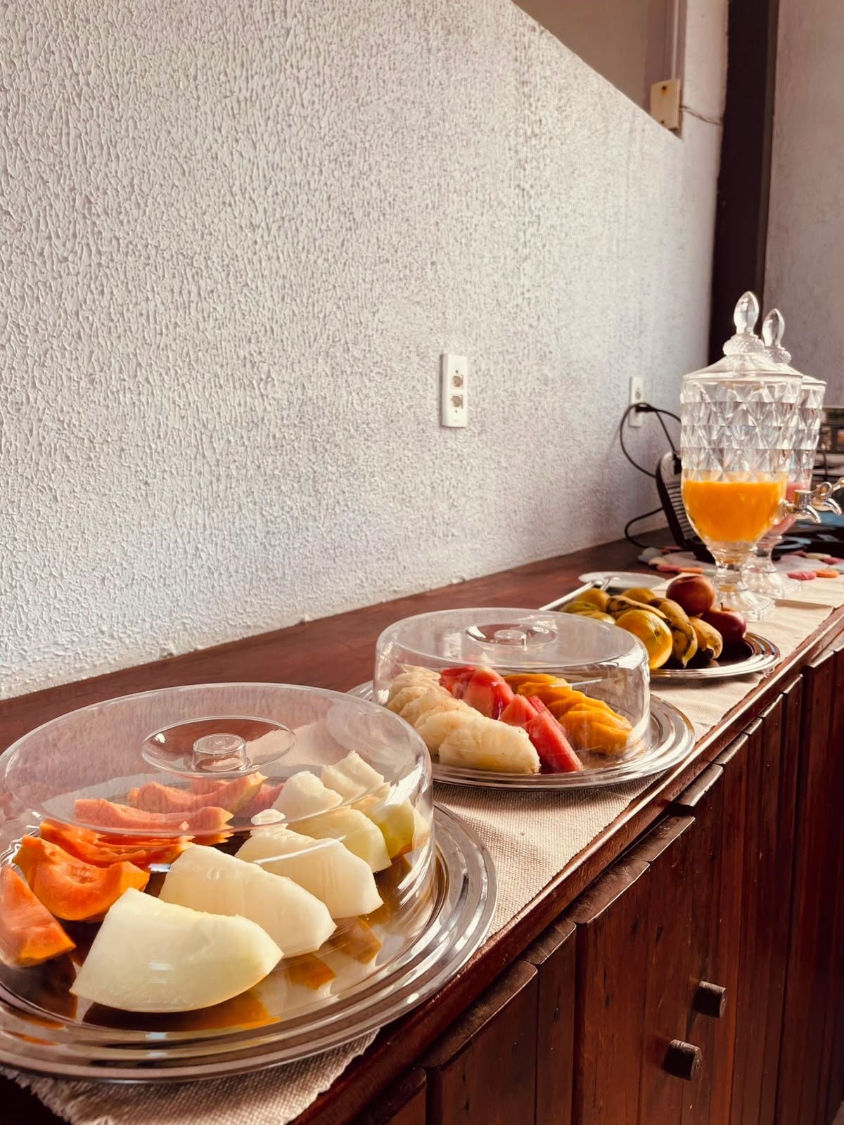 Un bufé de desayuno con platos cubiertos de frutas, verduras y carnes.