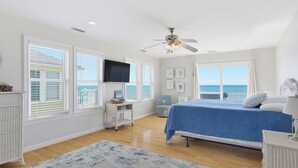 Ein Schlafzimmer mit Bett, Deckenventilator, Fernseher und Meerblick.