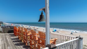 Eine Holzterrasse mit orangefarbenen Stühlen und einer Glocke.