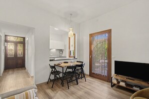 A modern kitchen with a dining area, a TV, and a wooden floor. - Holiday Home 'Il Melograno': Private Terrace, Private Parking, Wi-Fi, and Air Conditioning (Venezia)