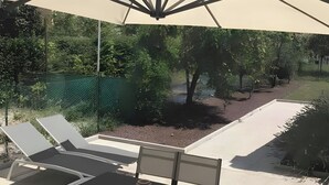 A patio area with a table and chairs, a large umbrella, and a view of a garden and trees. - Holiday Home 'Il Melograno': Private Terrace, Private Parking, Wi-Fi, and Air Conditioning (Venezia)