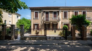 A two-story building with a balcony, a gated entrance, and a clear sky. - Holiday Home 'Il Melograno': Private Terrace, Private Parking, Wi-Fi, and Air Conditioning (Venezia)