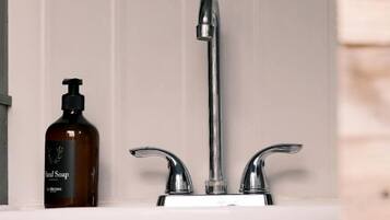 A bathroom with a white sink, a chrome faucet, and a bottle of soap.